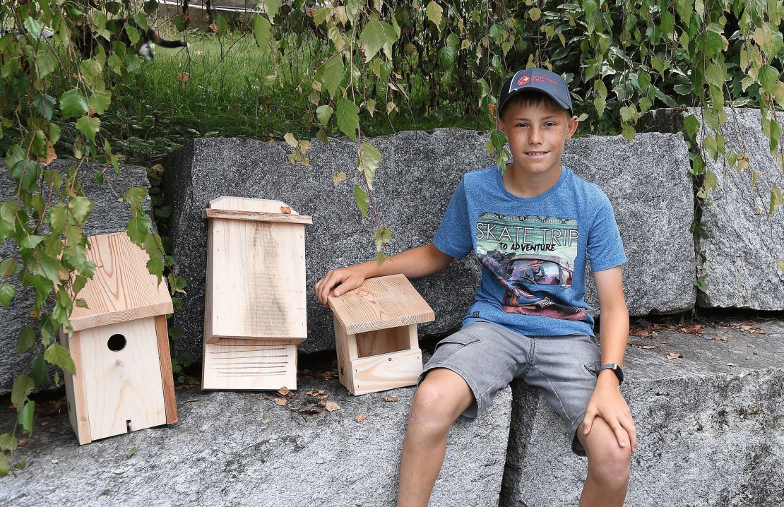 Jonas Bischof zeigt links einen Nistkasten, in der Mitte einen Fledermauskasten und rechts einen offenen Nistkasten.